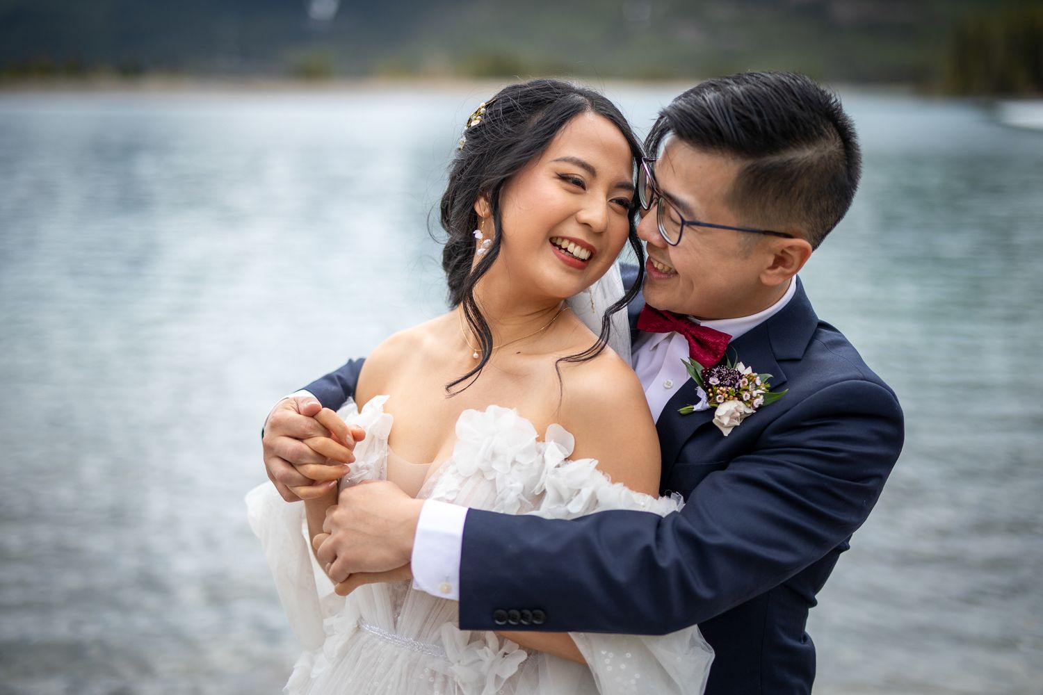 A couple shares intimate moments by Bow river in Canmore during their wedding photo session.
