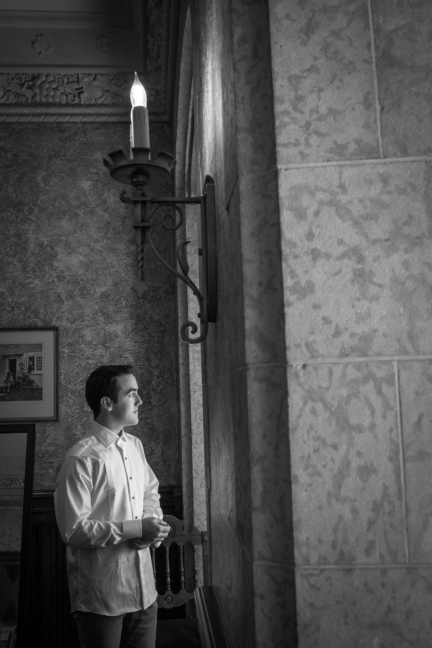 A figure in a white shirt stands by candlelight in a stone-walled room, shown in four sequential black and white photos in Banff