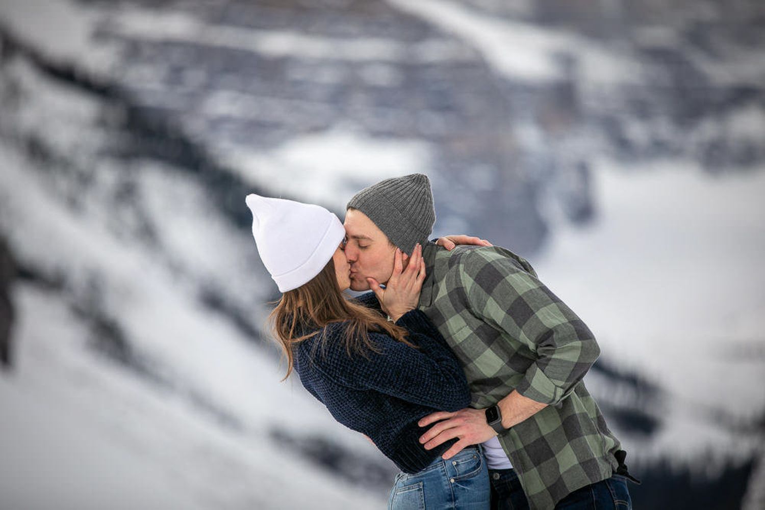 A couple embraces while enjoying a snowy winter mountain landscape at Lake Louise in the Canadian Rockies.