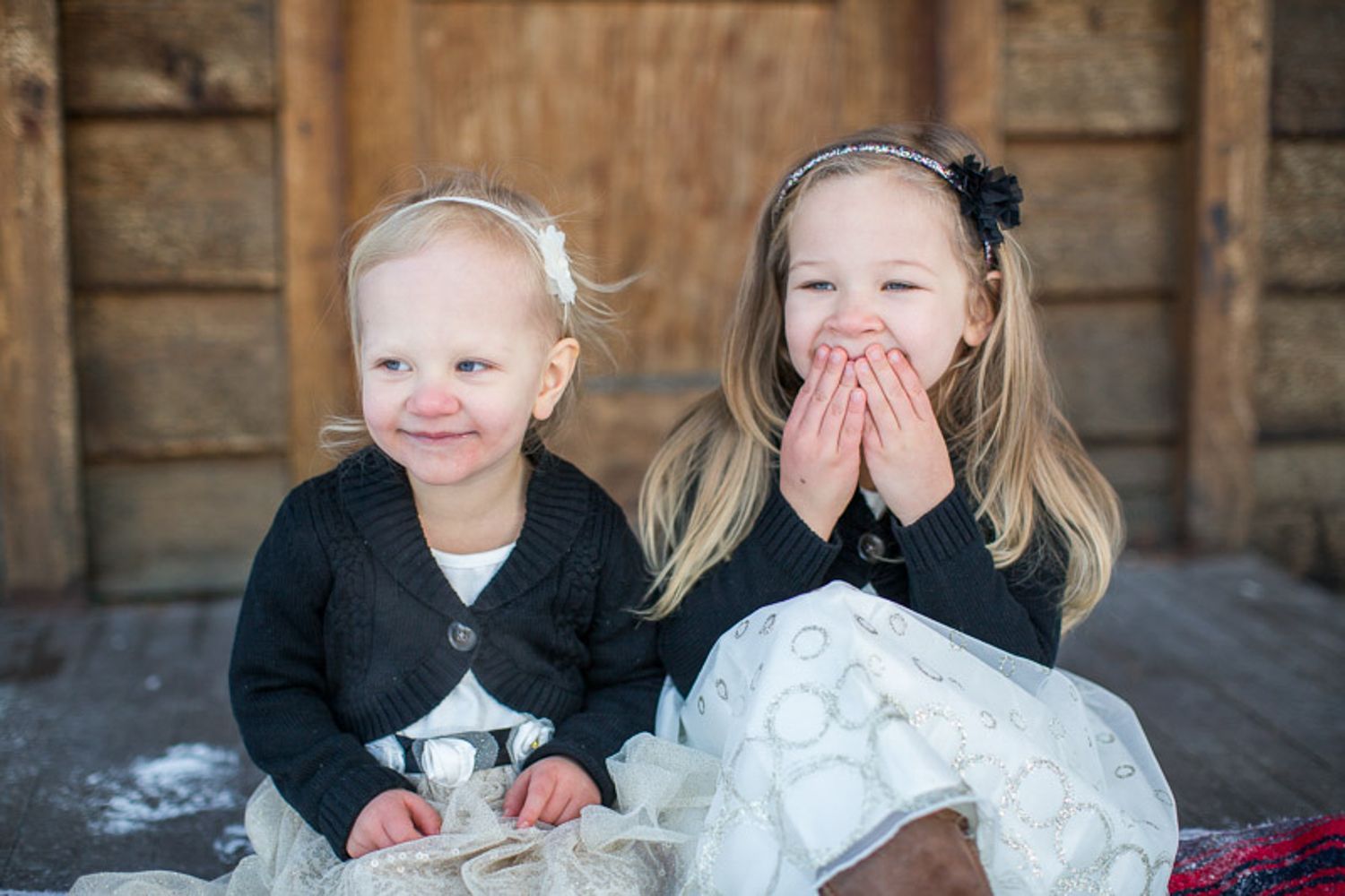 Children sitting together on stone steps share joyful laughter during an outdoor photo session in Banff, AB.