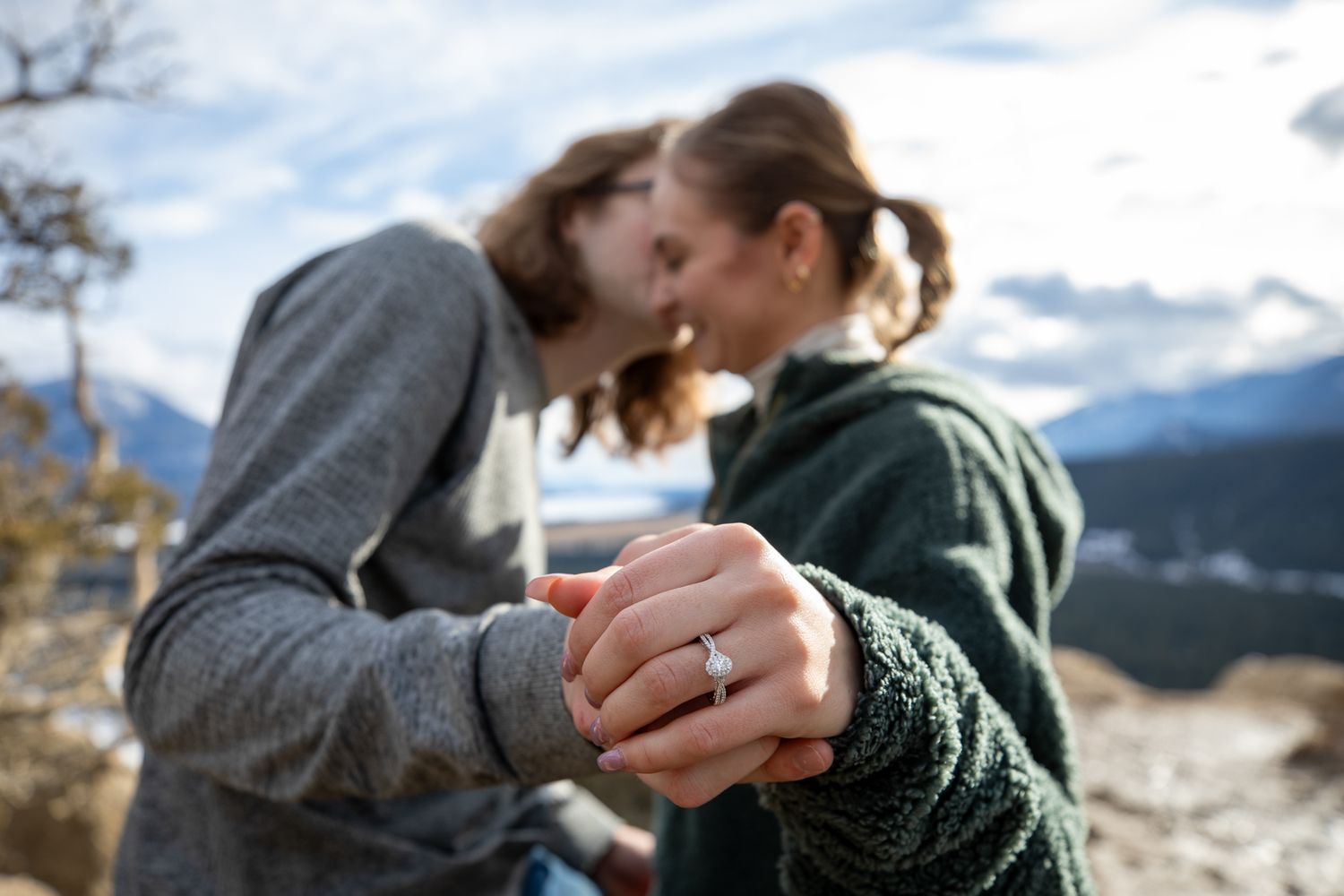 A couple holds hands while admiring a scenic mountain landscape on a cloudy day at Fairmont Hot Springs, BC