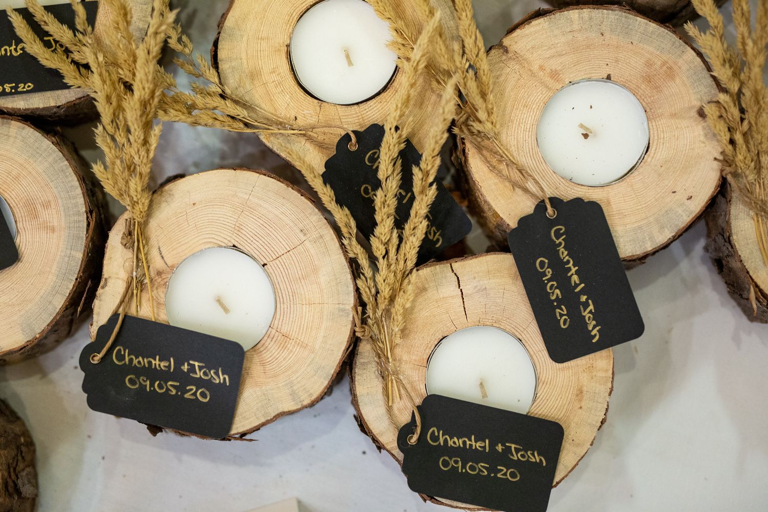 Rustic wooden log slice wedding favors with white tealight candles, wheat stalks, and personalized chalkboard gift tags. Silvertip Resort.