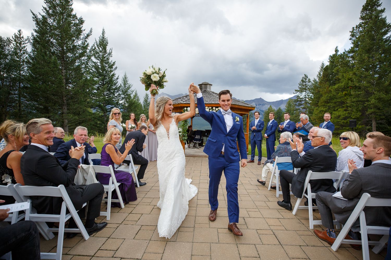 Wedding celebration on stone patio with guests in navy blue attire and mountain backdrop at Silvertip resort in Canmore.