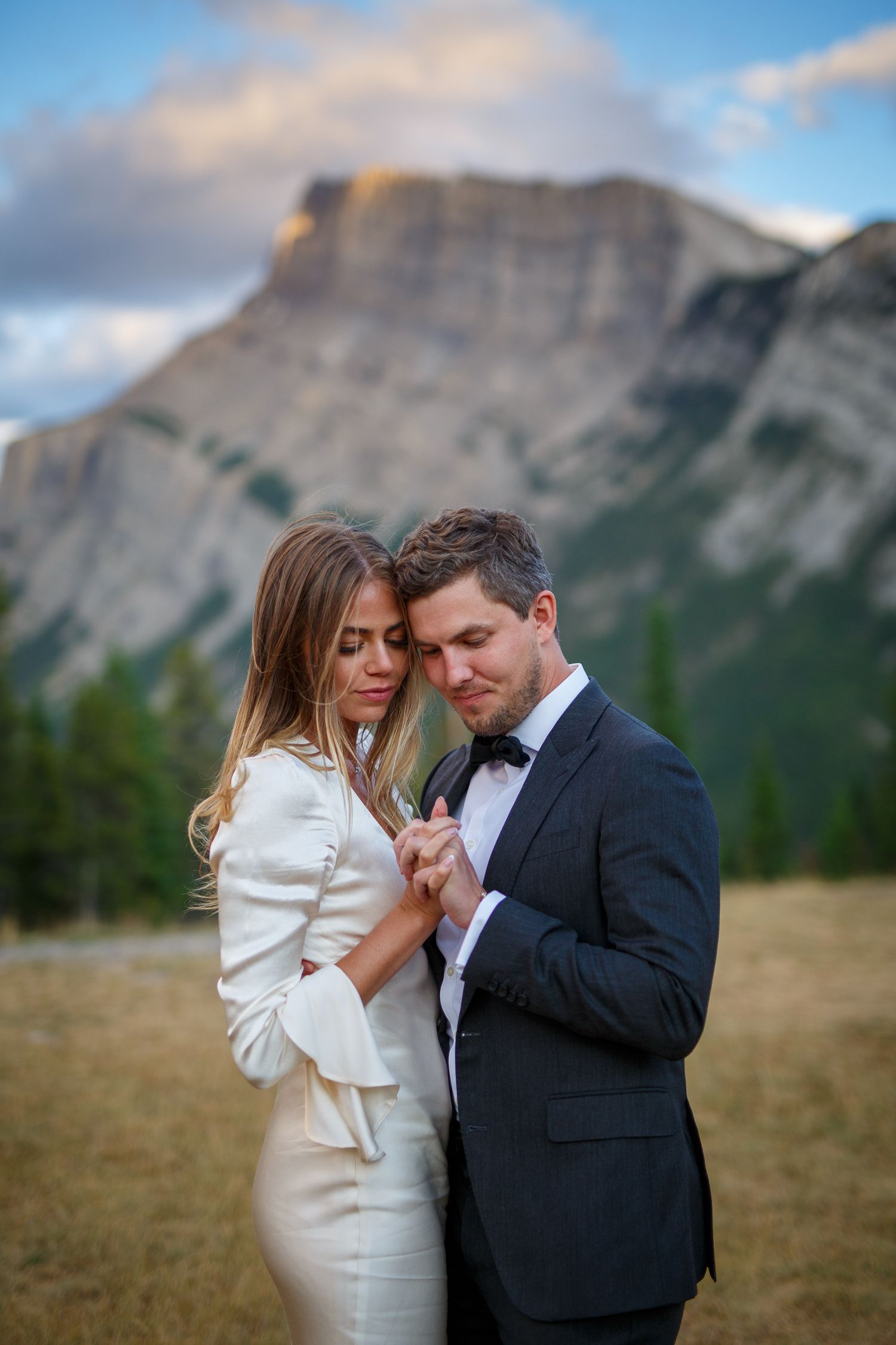 Romantic wedding portraits in mountain field during golden hour in Banff tunnel mountain reservoir, Banff, Alberta