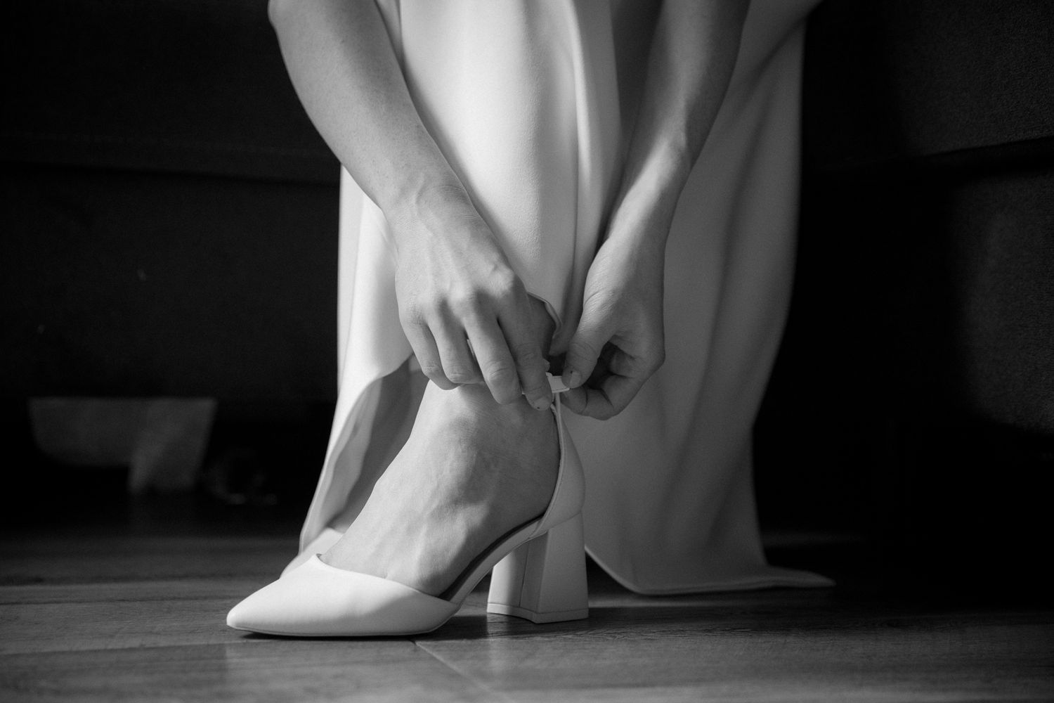 A series of black and white photos showing close-up details of elegant bridal shoes and wedding dress hems.