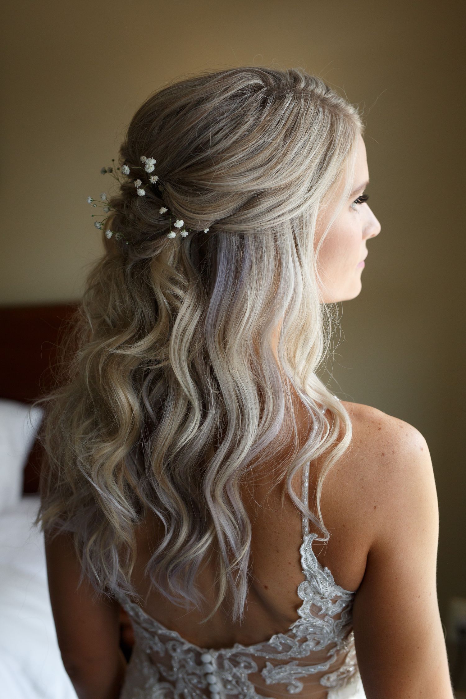 Close-up views of a bridal hairstyle featuring wavy platinum blonde hair with delicate pearl accessories and lace details.
