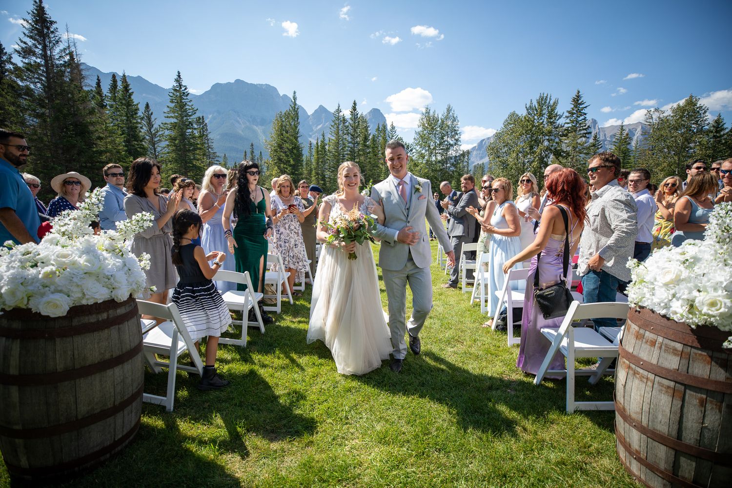 An outdoor mountain wedding ceremony in Canmore with stunning Rocky Mountain peaks and evergreen trees in the background.