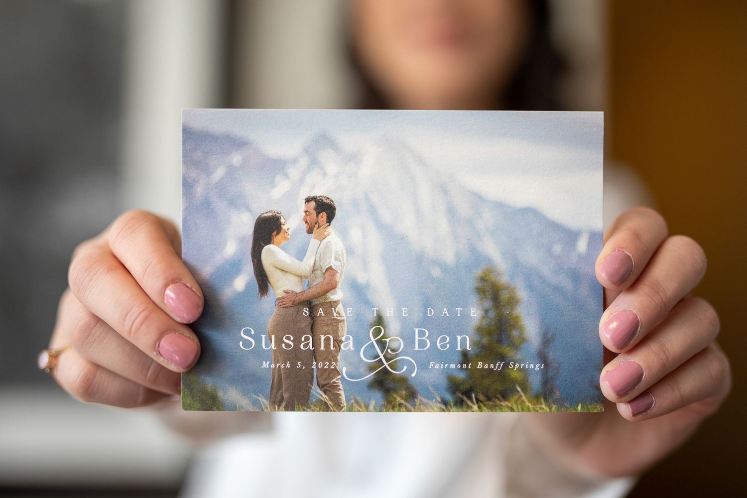 Hands holding a wedding photo album showing an elegant outdoor photoshoot with a couple in formal attire. Fairmont Banff Springs Hotel