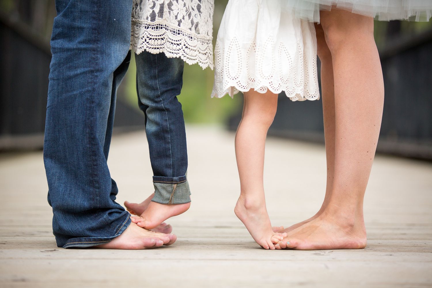 Close-up of feet showing a progression from baby to child to adult wearing jeans and dresses Canmore old bridge.
