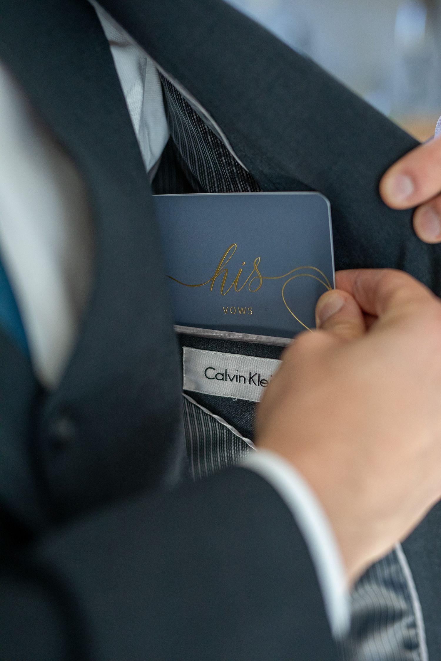 Close-up view of Calvin Klein suit jacket sleeve being adjusted to show brand label details by a groom in Canmore.