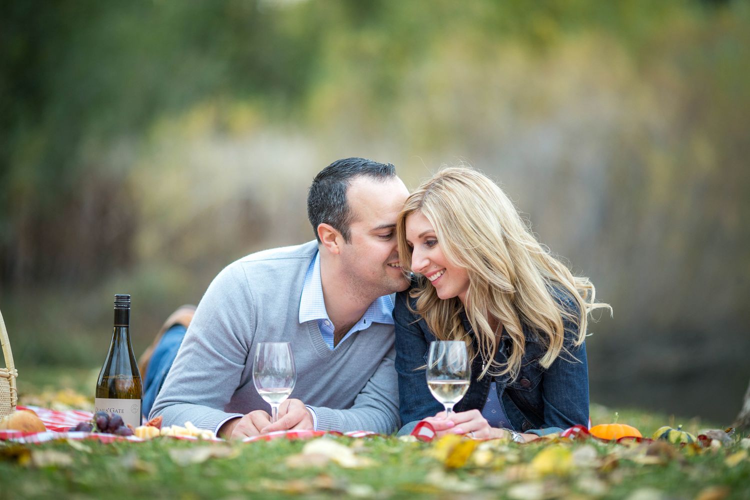 A couple shares an intimate moment during a romantic outdoor picnic with wine and snacks on a fall day in Calgary, AB.