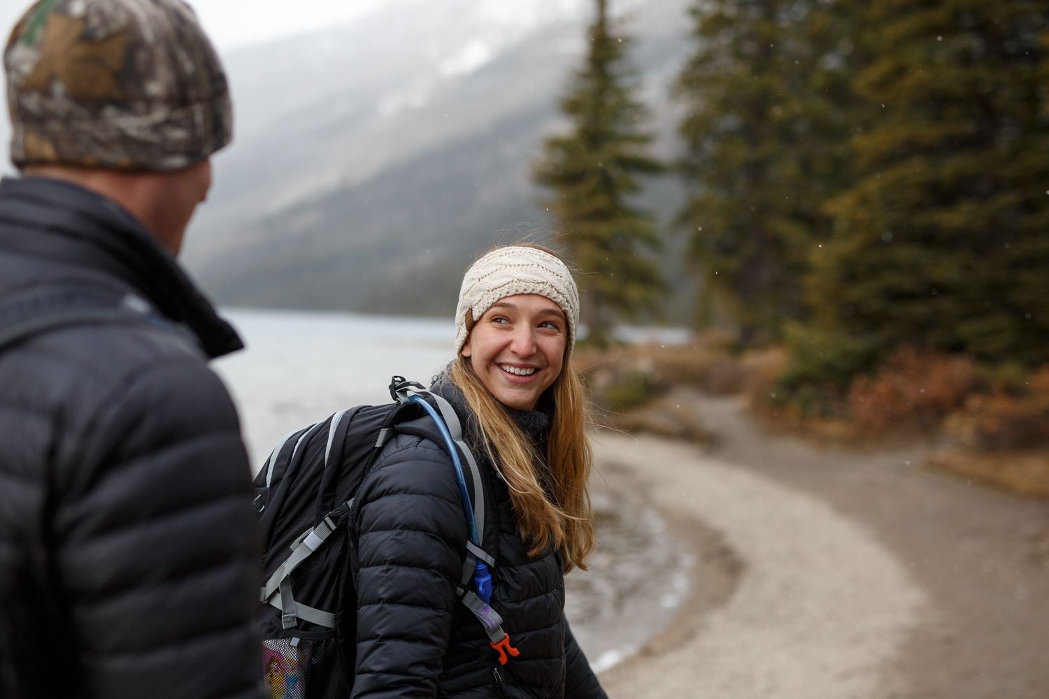 A couple walks along a scenic mountain lake trail on a cloudy winter day in the wilderness  at Bow Lake in Banff National Park.