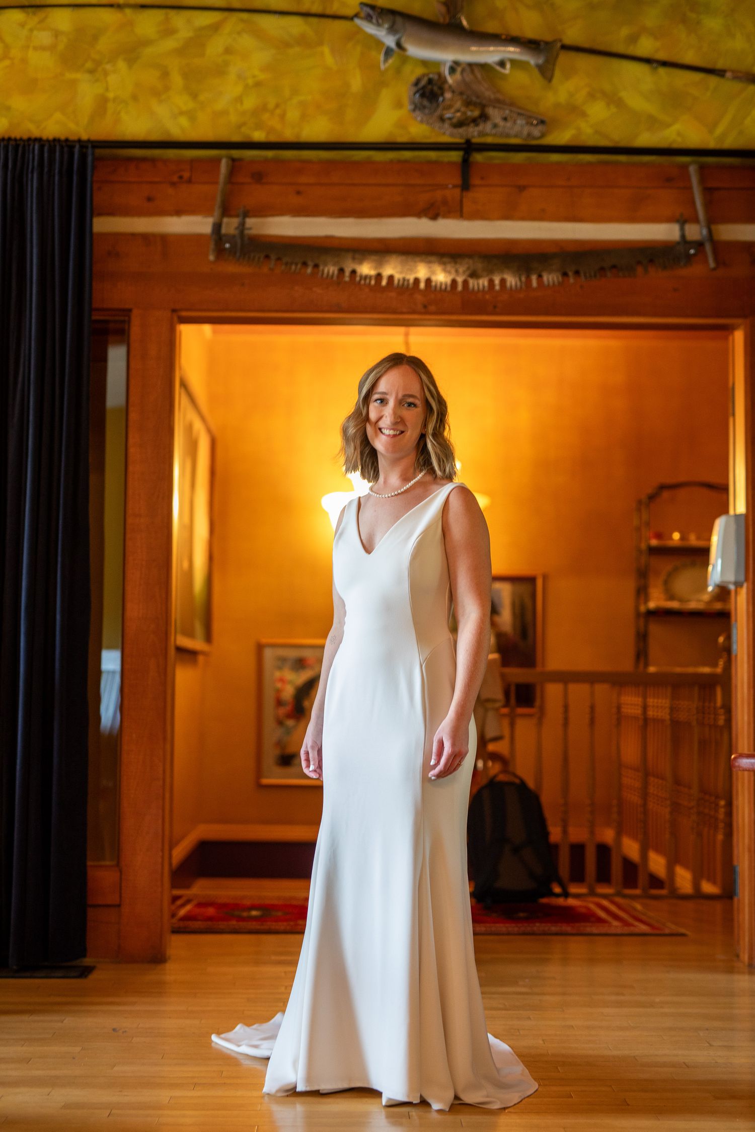 A flowing white dress twirls gracefully in a warmly lit room with wooden floors and staircase in the background.