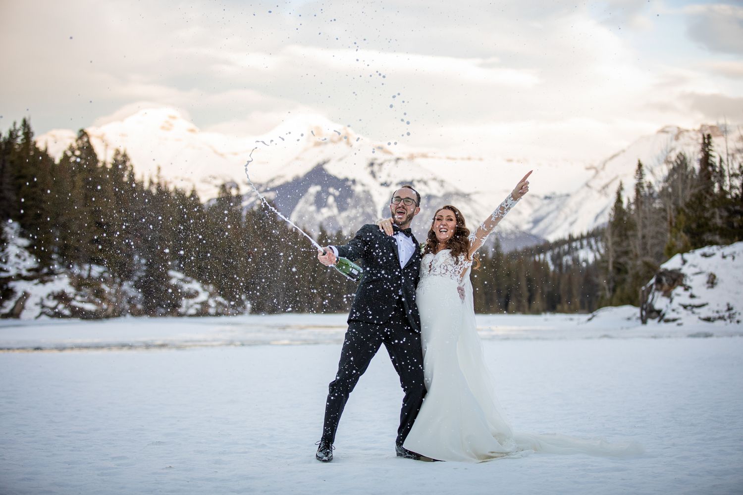 Snow-covered mountain peaks rise majestically behind a frozen lake in a serene winter landscape. Bow Falls in Banff.