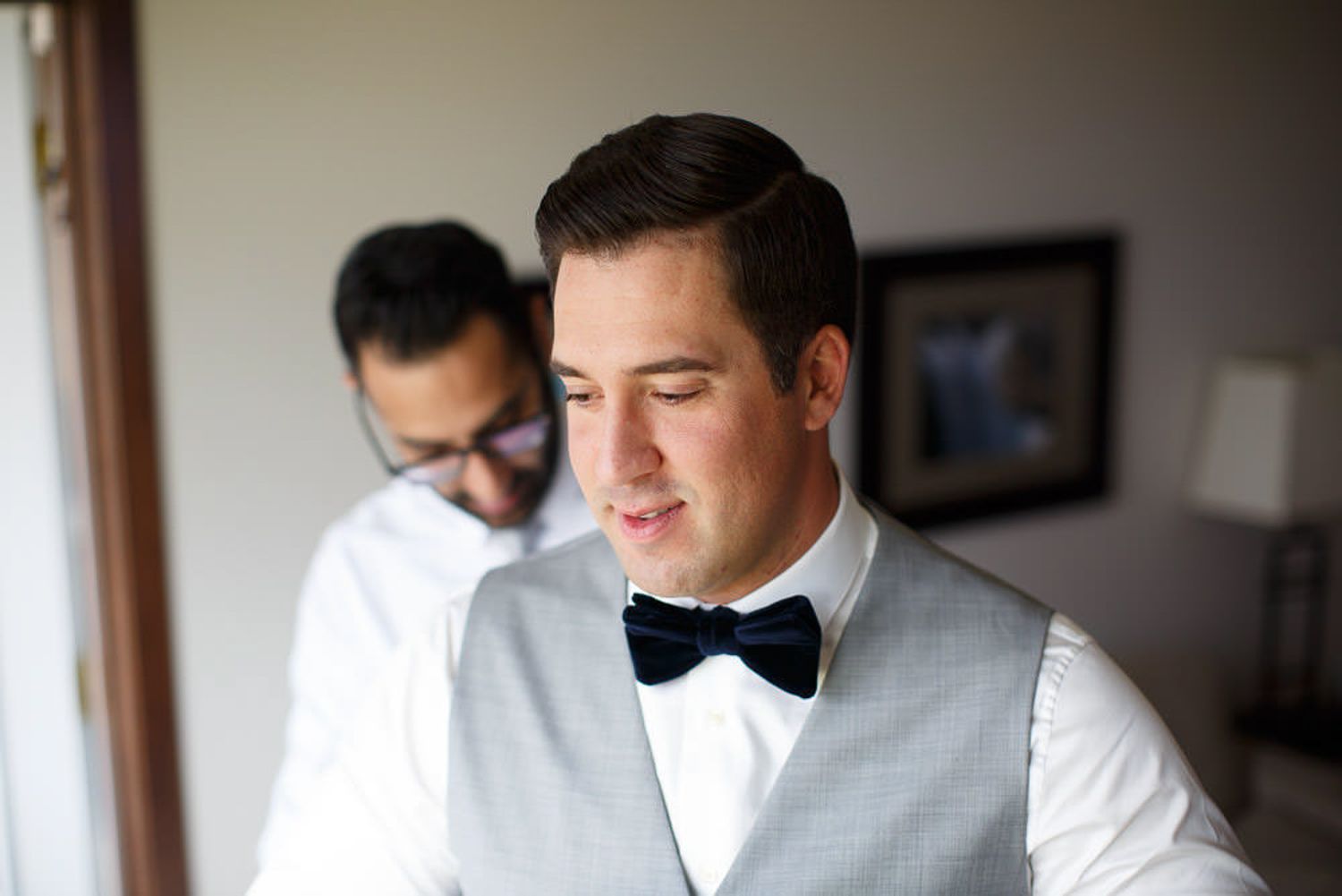 Groomsmen in white dress shirts and black bow ties getting ready before a wedding ceremony at Solara resort in Canmore, AB.