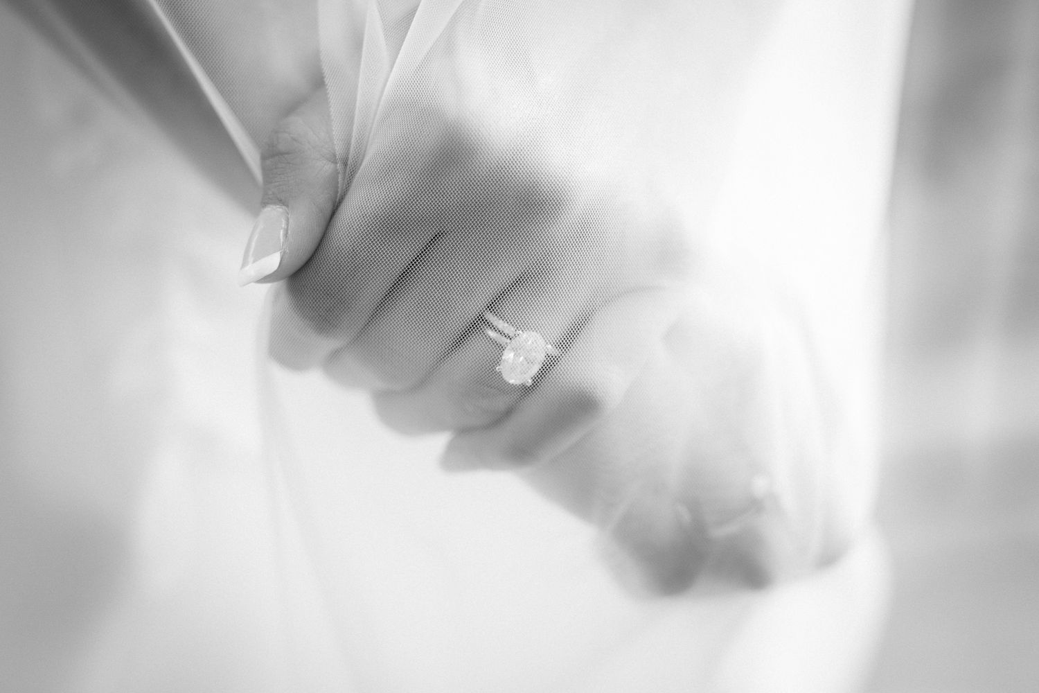 A black and white image of a bride showing her ring with veil covering her hands at Silvertip resort in Canmore, Alberta.