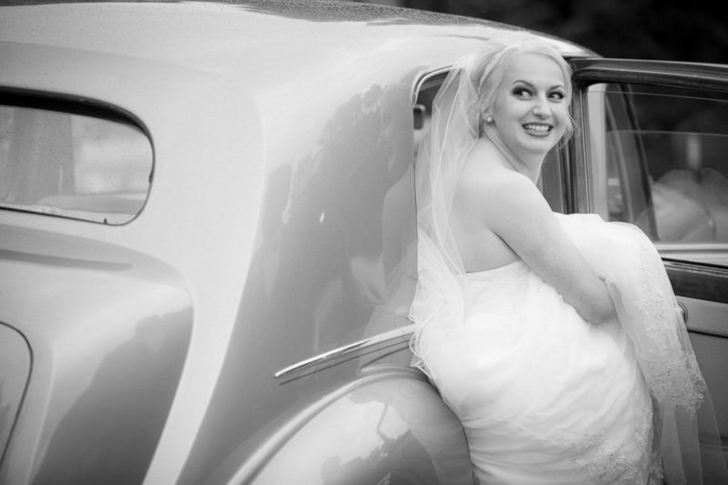 A bride in a white wedding dress poses in and around a classic car during a photo session in Banff, Alberta.