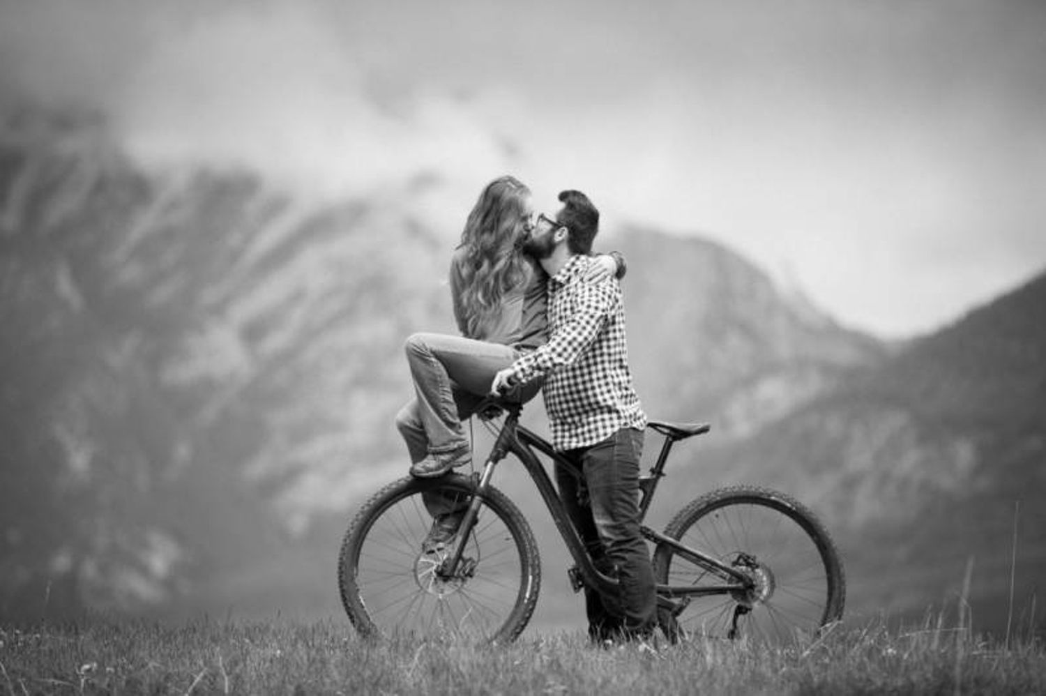 A series of black and white romantic silhouette photos showing couples embracing and cycling against scenic backgrounds in Canmore, AB.