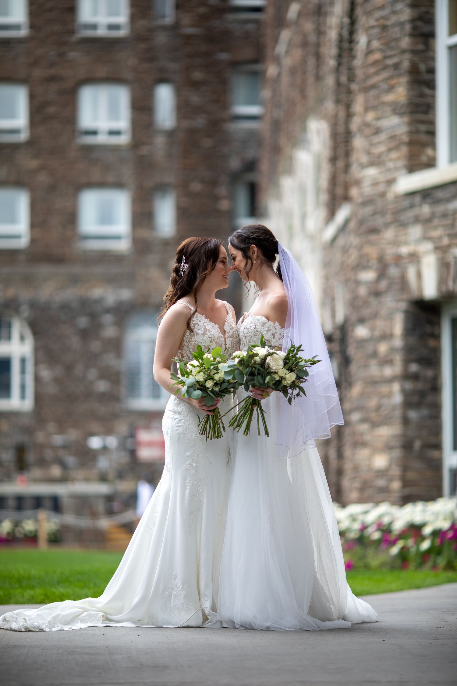 Two beautiful brides in white dresses close together with flowers after a celebration at the Fairmont Banff Springs Hotel. Banff Alberta.