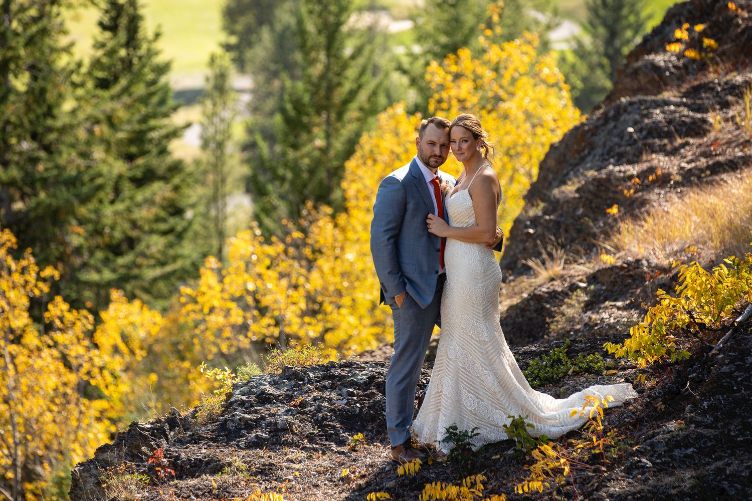A couple shares a romantic moment surrounded by vibrant yellow fall foliage and evergreen trees in a mountain setting of Panorama resort, BC