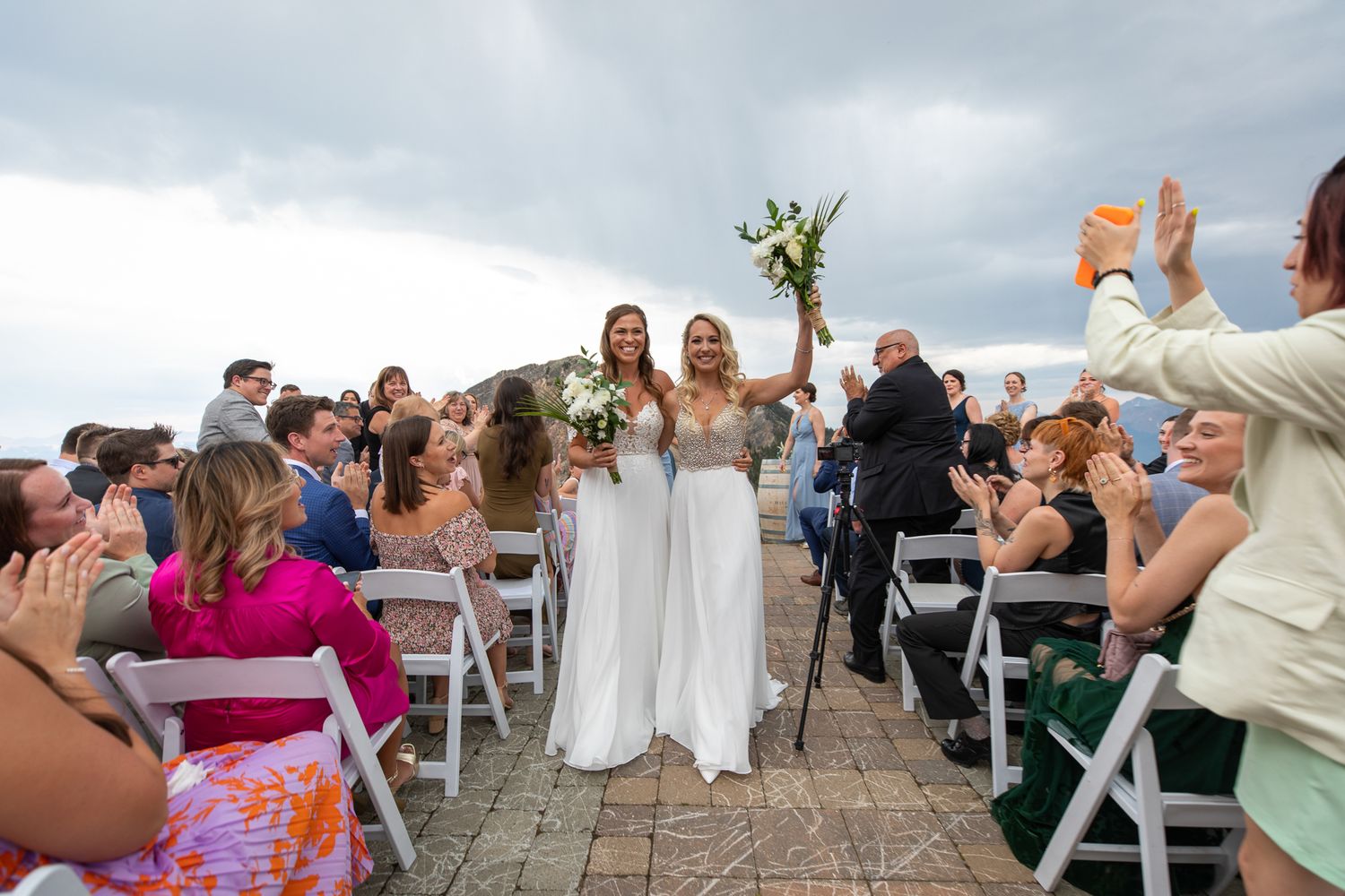 Two bride exiting a ceremony site with guests celebrating the newly weds at Kicking Horse resort in Golden, BC