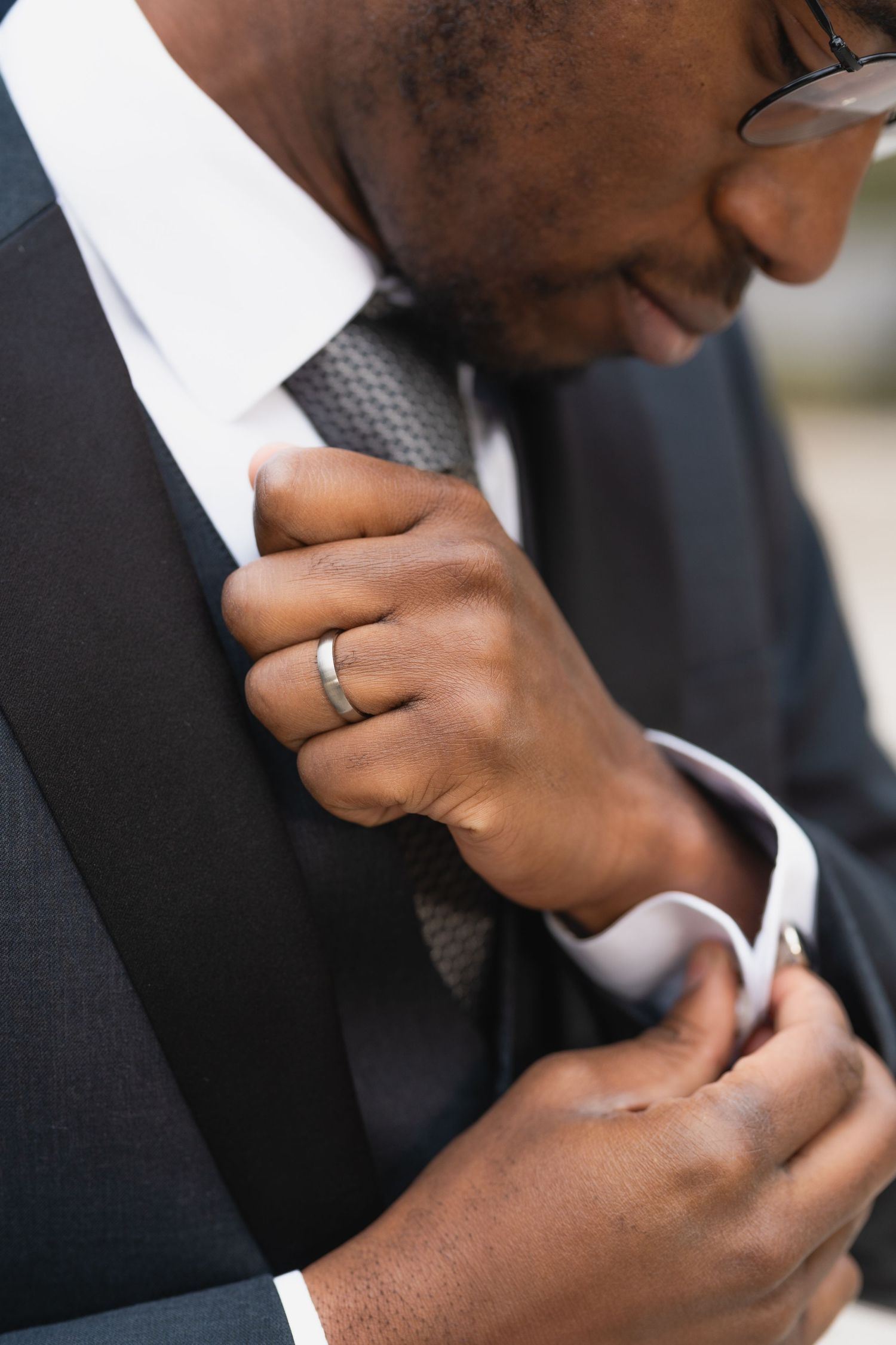 Close-up detail shot of adjusting a necktie and wedding ring.