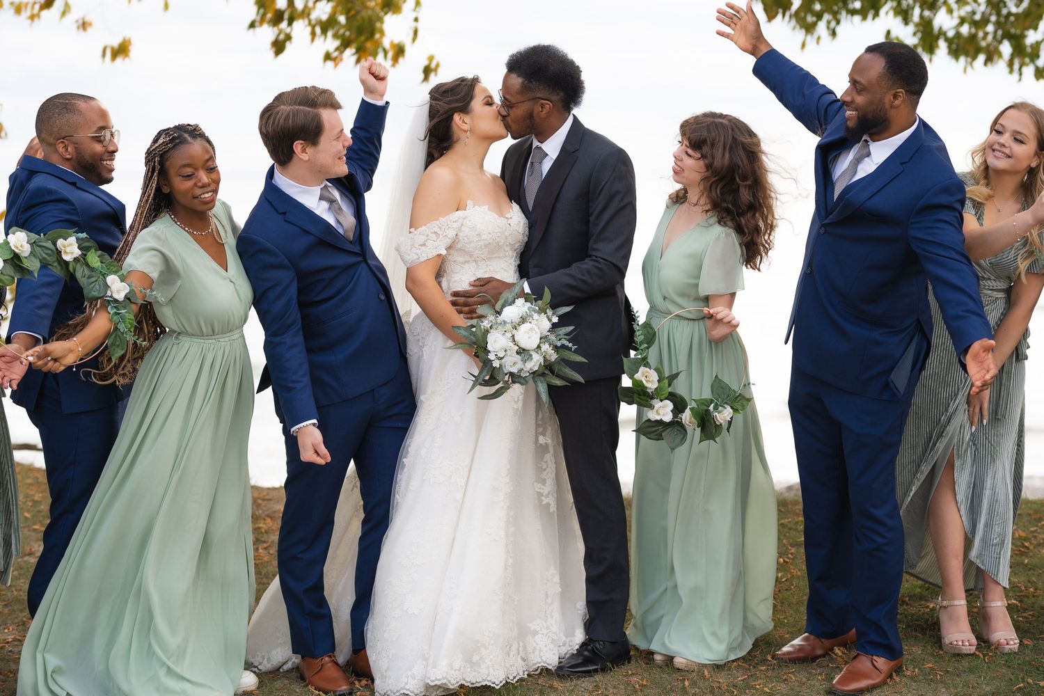 Wedding party in navy blue and sage green attire celebrating outdoors.