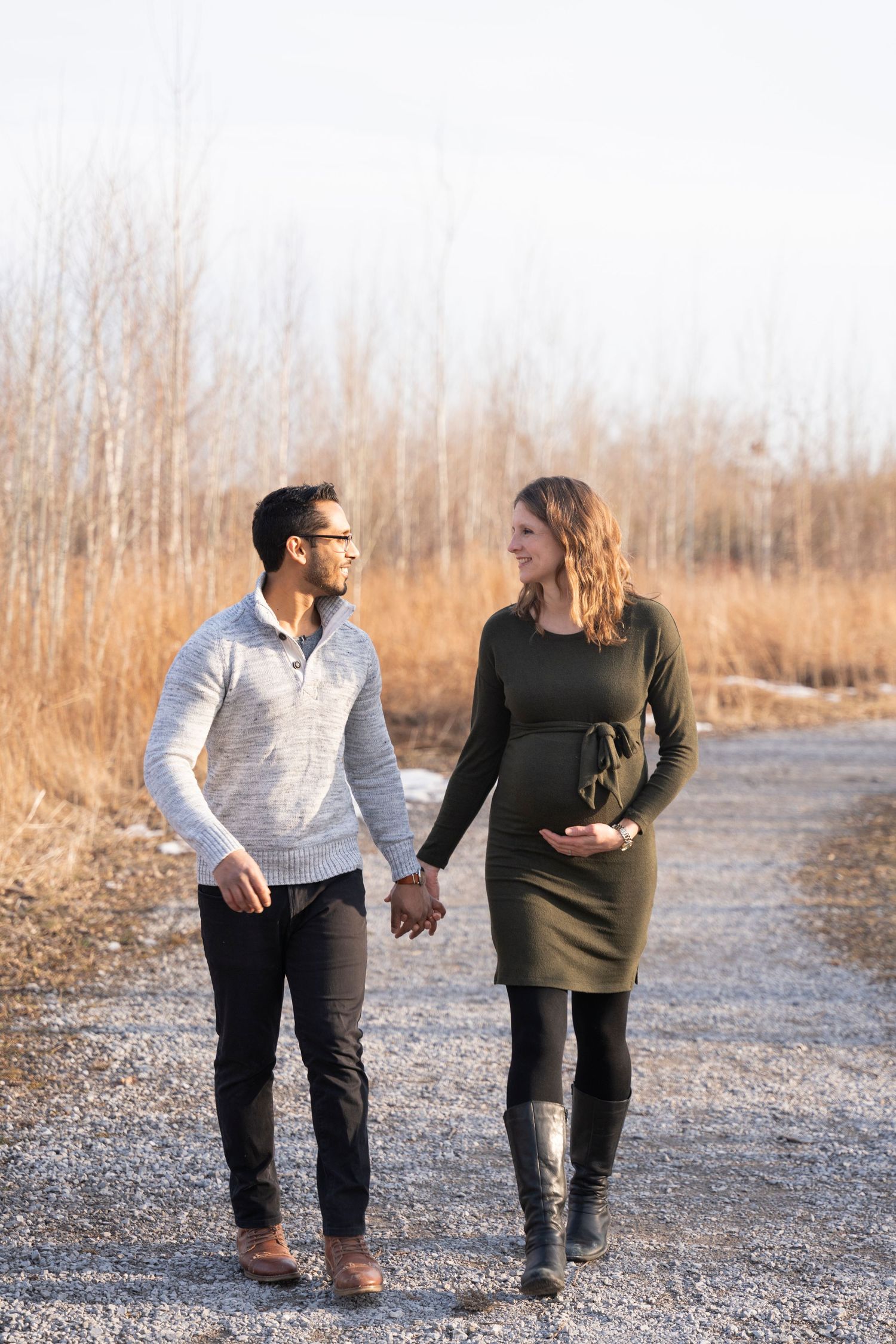 Couple taking a winter walk together on a gravel path surrounded by tall grass.
