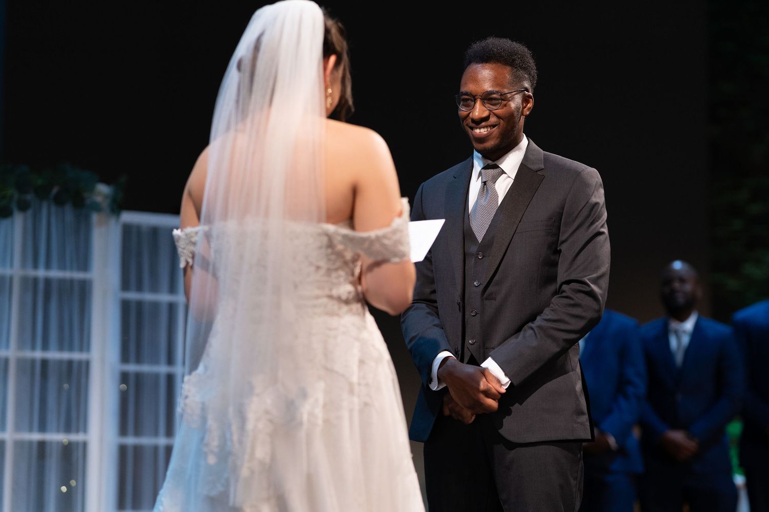 A wedding ceremony moment captured with the bride reading vows at the altar.