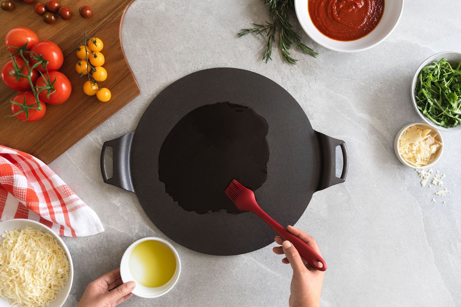 Overhead view of a dark cast iron pan with a red spatula, surrounded by fresh ingredients.