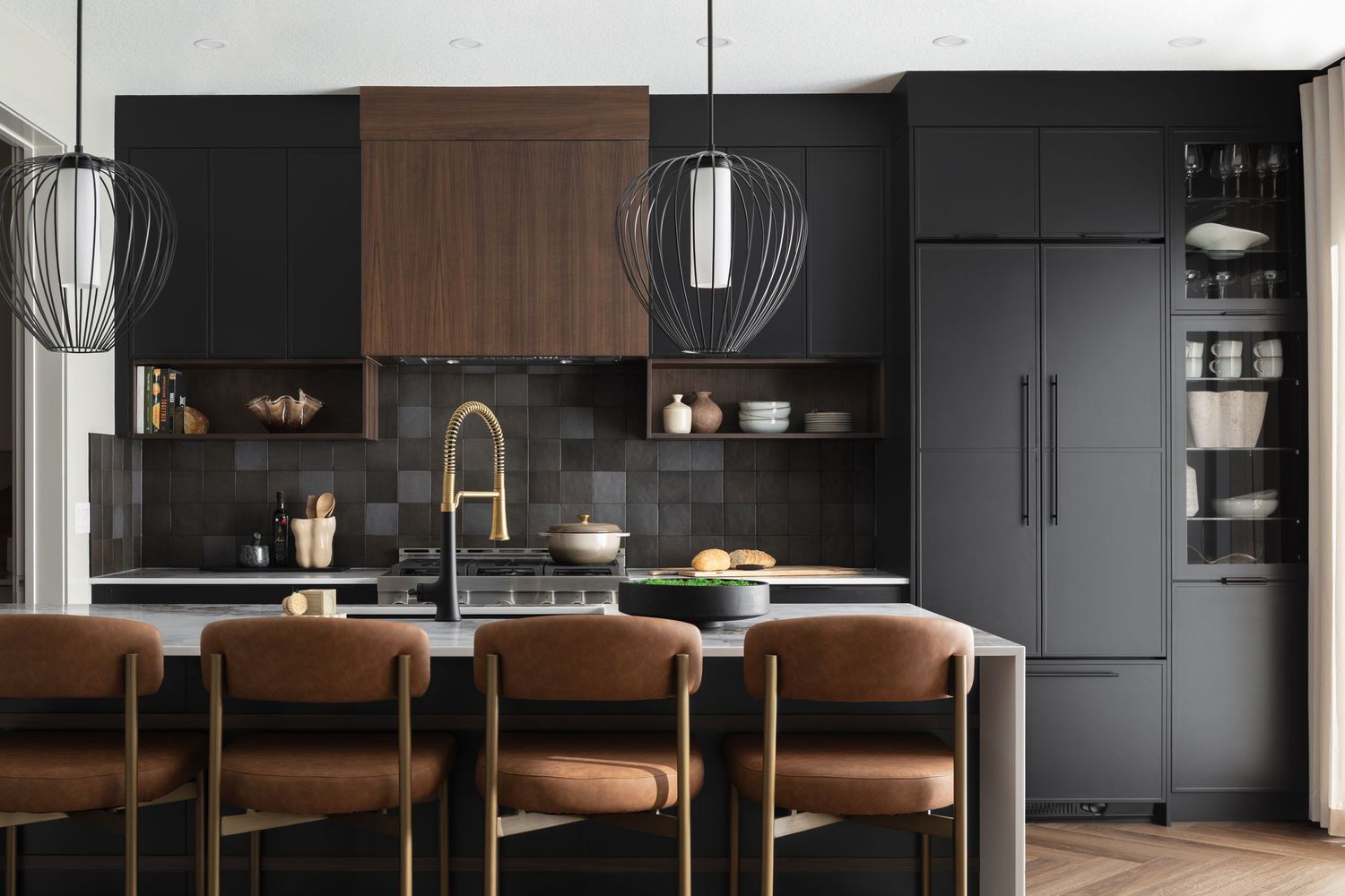 Modern kitchen with black cabinets, walnut accents, marble island, brass fixtures, and cage pendant lights by Rebecca Frick Photography.