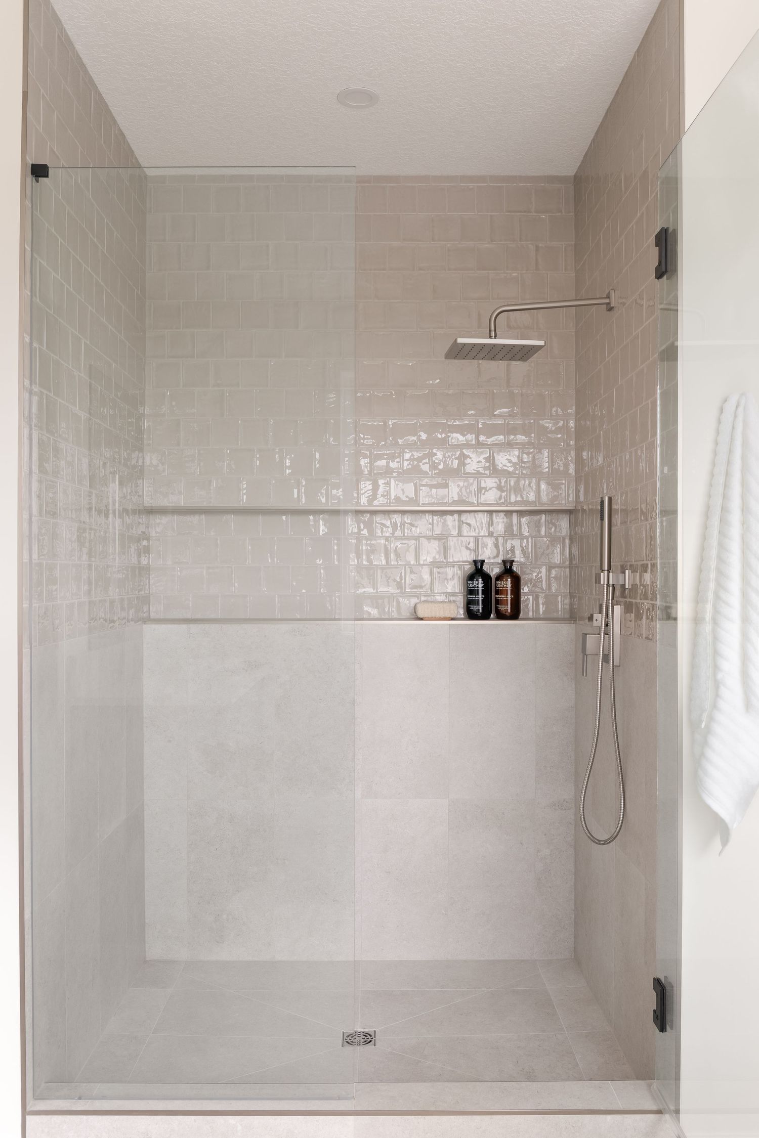 Modern walk-in shower with white subway tiles, rain showerhead, and glass enclosure.