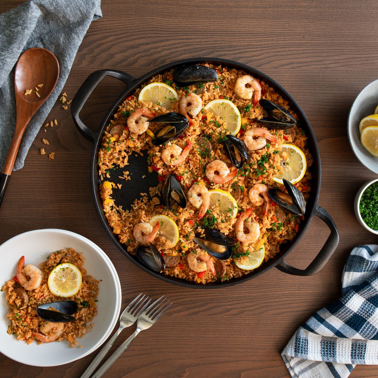 Overhead view of seafood paella with shrimp, mussels, and lemon slices in a large pan.