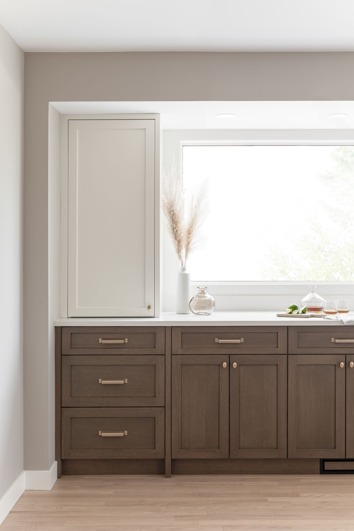 Two-tone kitchen with dark brown lower cabinets, cream upper cabinet, and white quartz countertop.