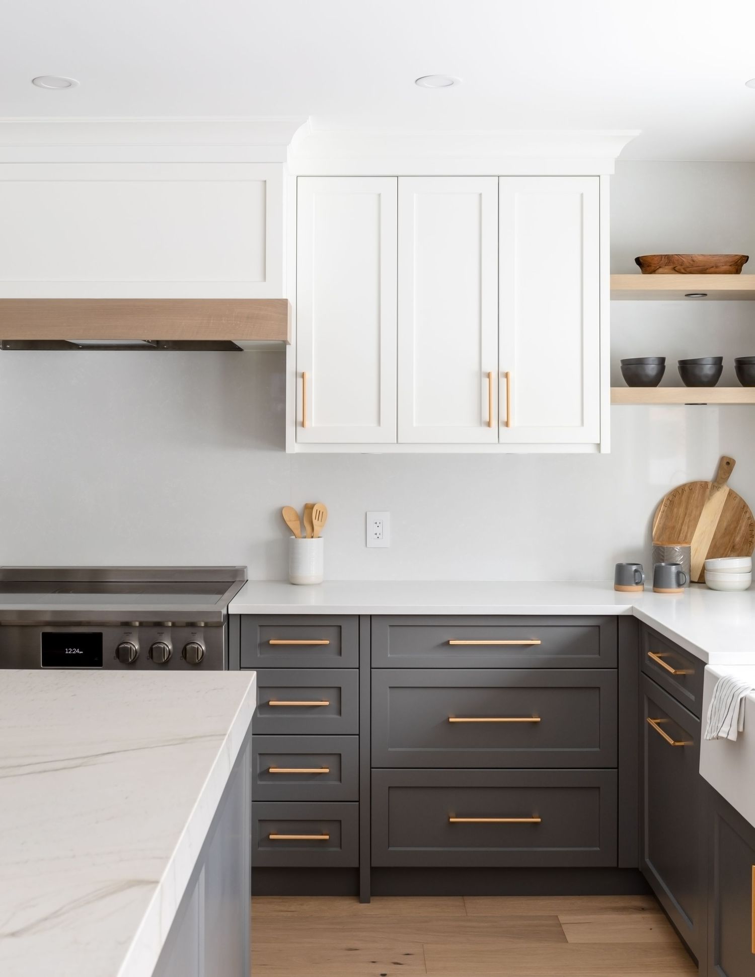 Two-tone kitchen with dark lower cabinets, white uppers, gold hardware, and marble countertops.