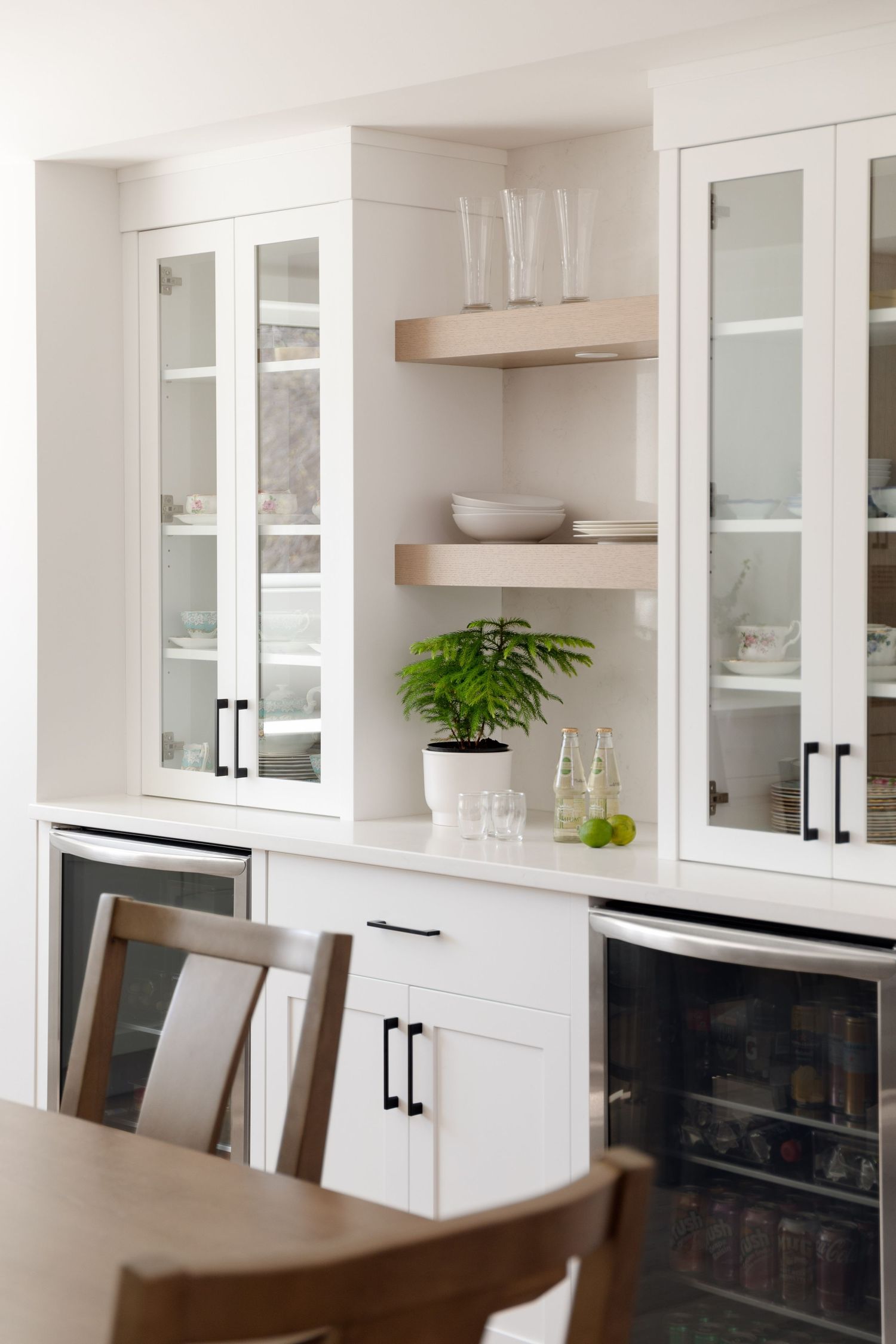 White built-in cabinetry with glass doors, open shelves, wine fridge, and black hardware accents.