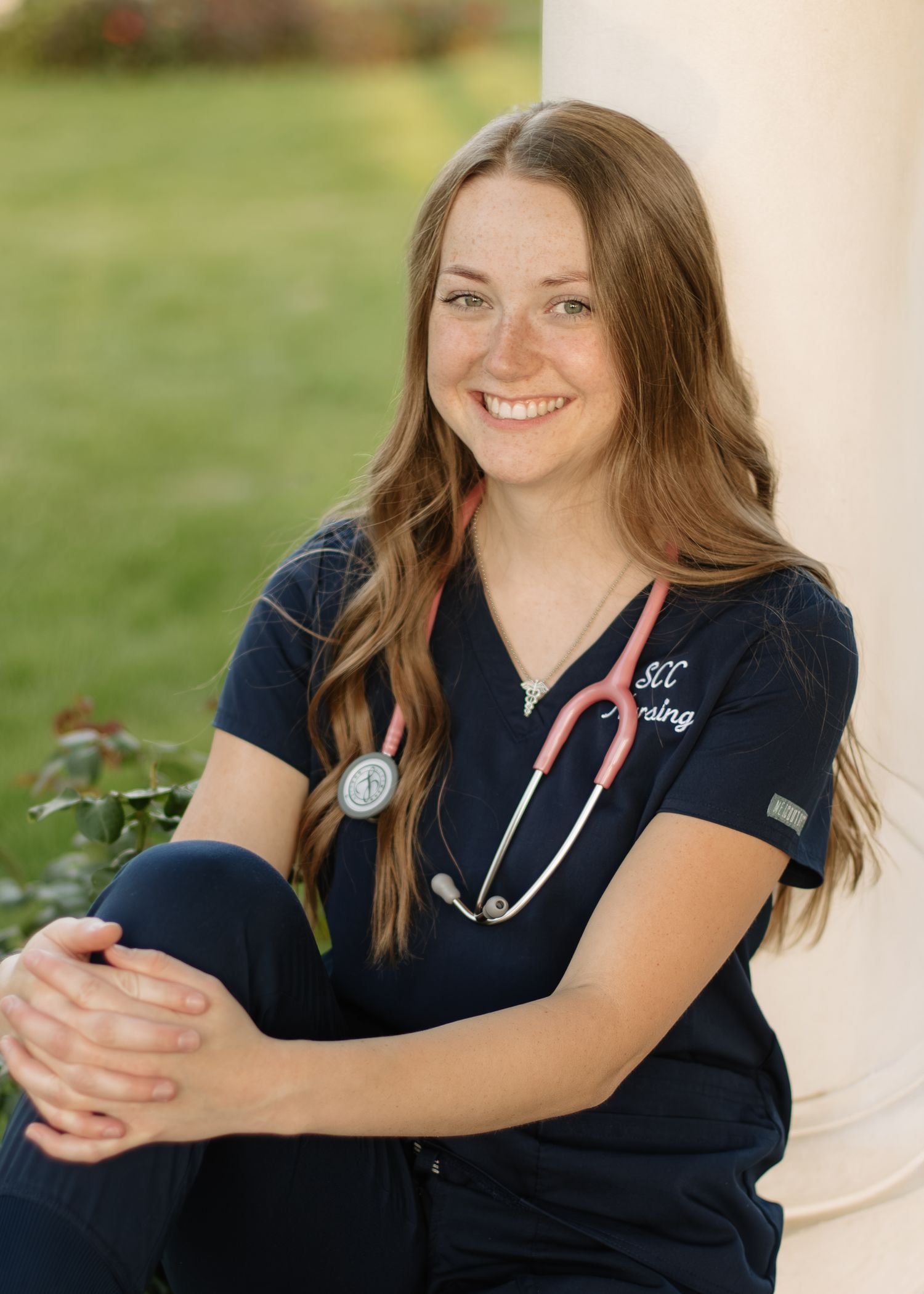 Healthcare professional in navy scrubs with stethoscope shown in a series of outdoor portrait poses.