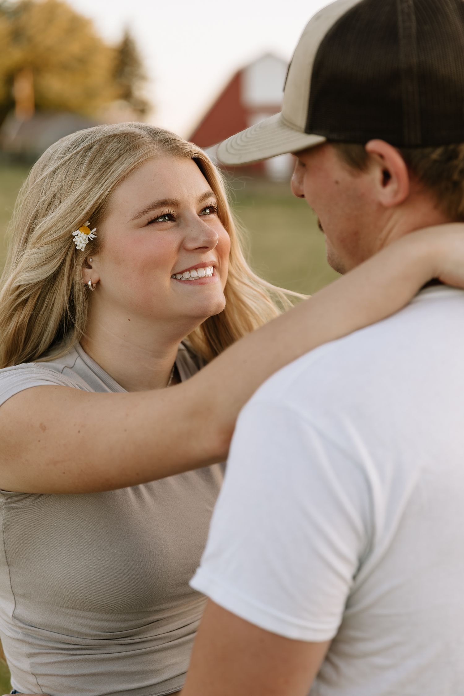 A couple shares a tender moment outdoors during a golden hour photoshoot in casual attire.