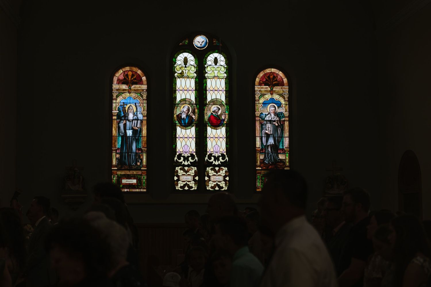 Stained glass windows in a church interior showcase colorful religious artwork and ornate architectural details.