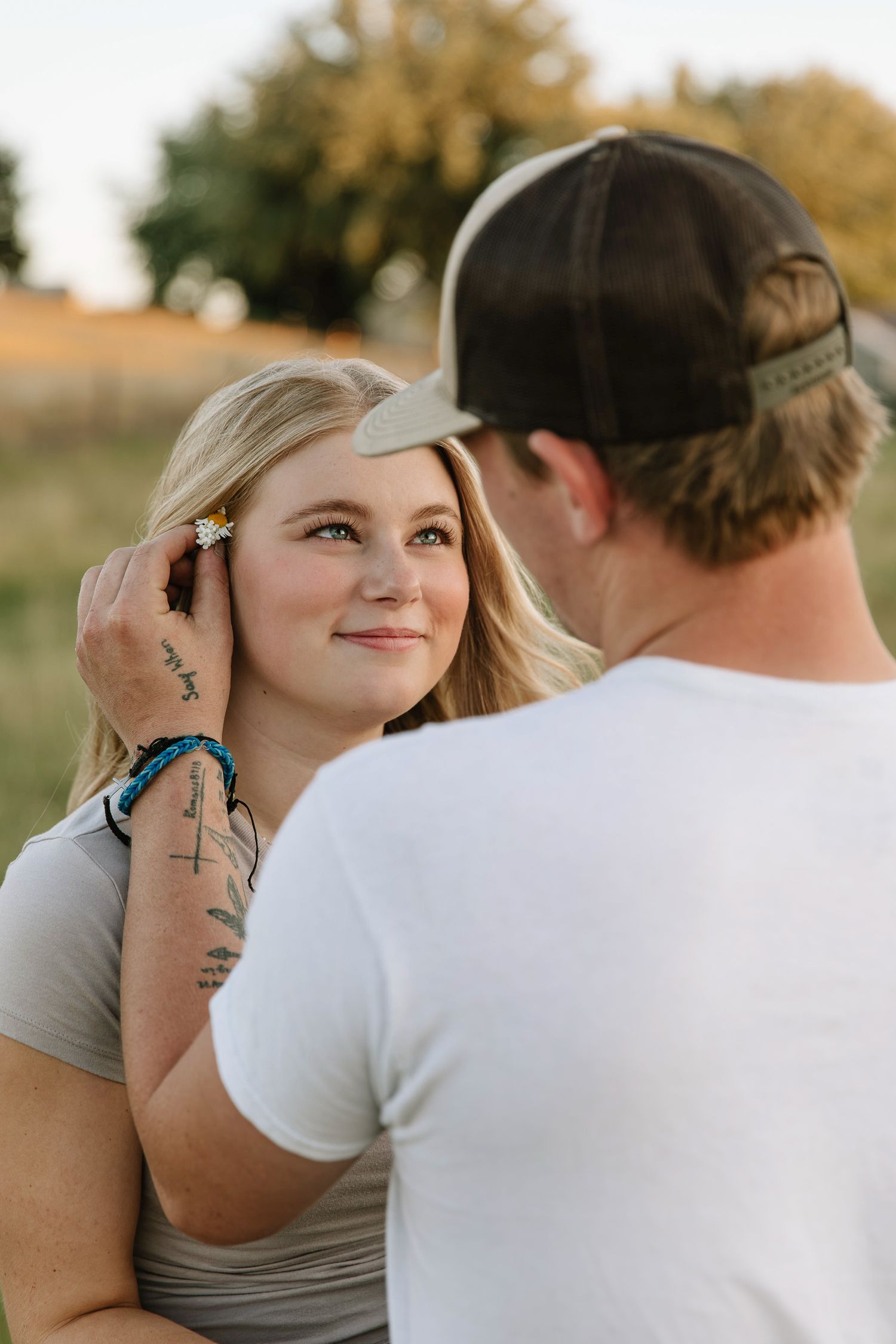 A couple shares an intimate moment outdoors with golden autumn foliage in the background.