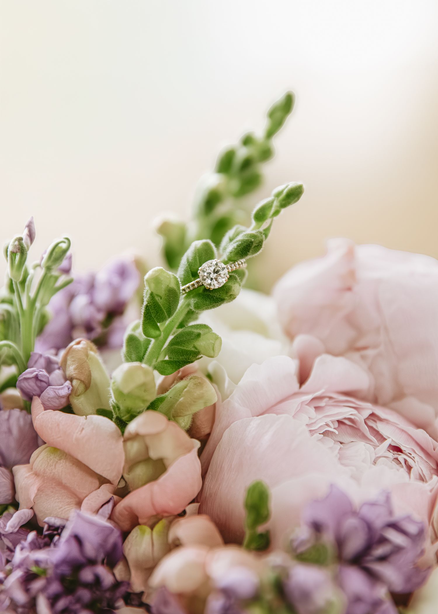 A delicate floral arrangement featuring soft pink peonies and purple snapdragons with fresh green foliage.