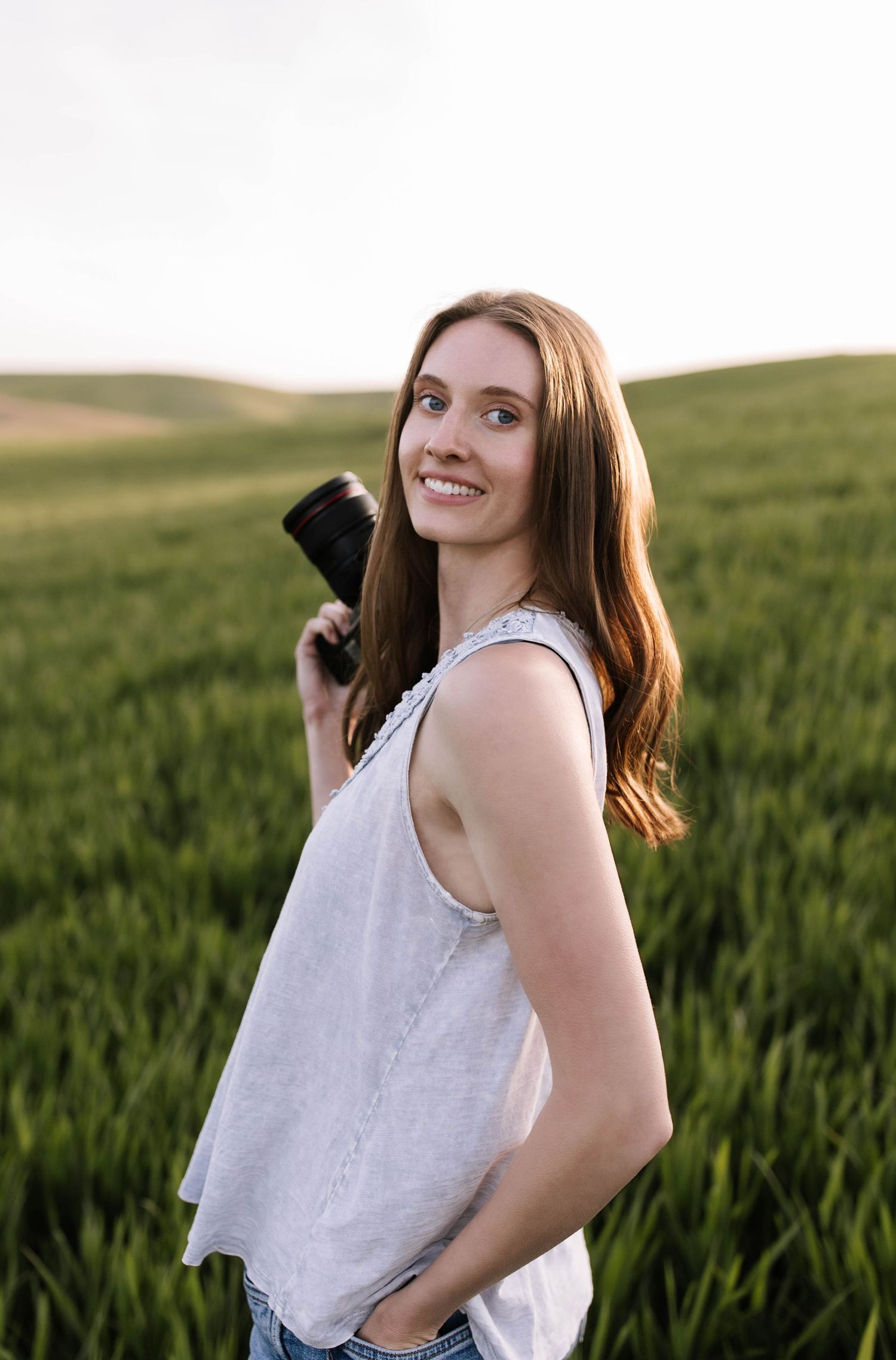 Person in white tank top enjoying a sunny day in a green wheat field.