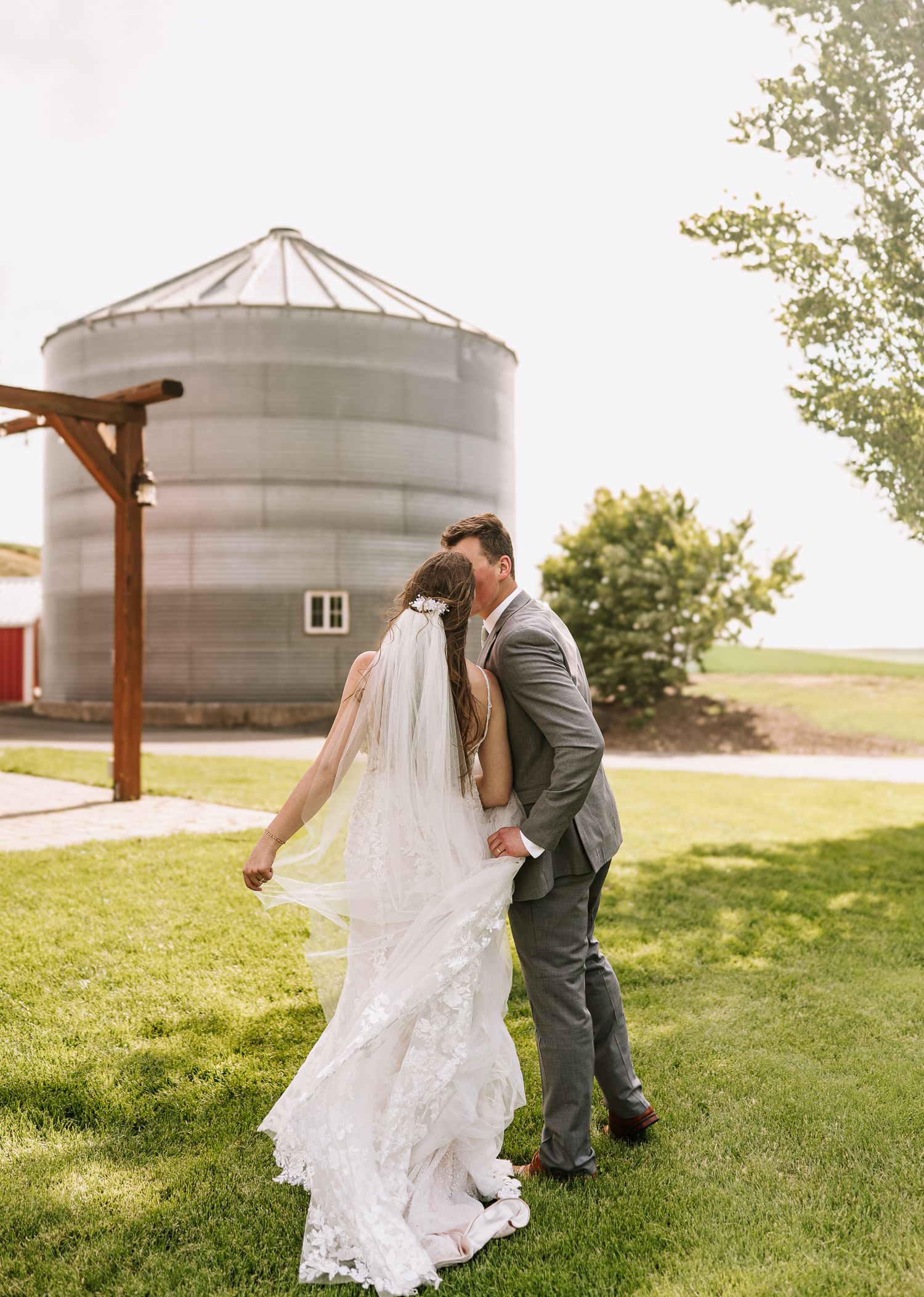 A couple shares an intimate moment in front of a rustic silo on their wedding day.