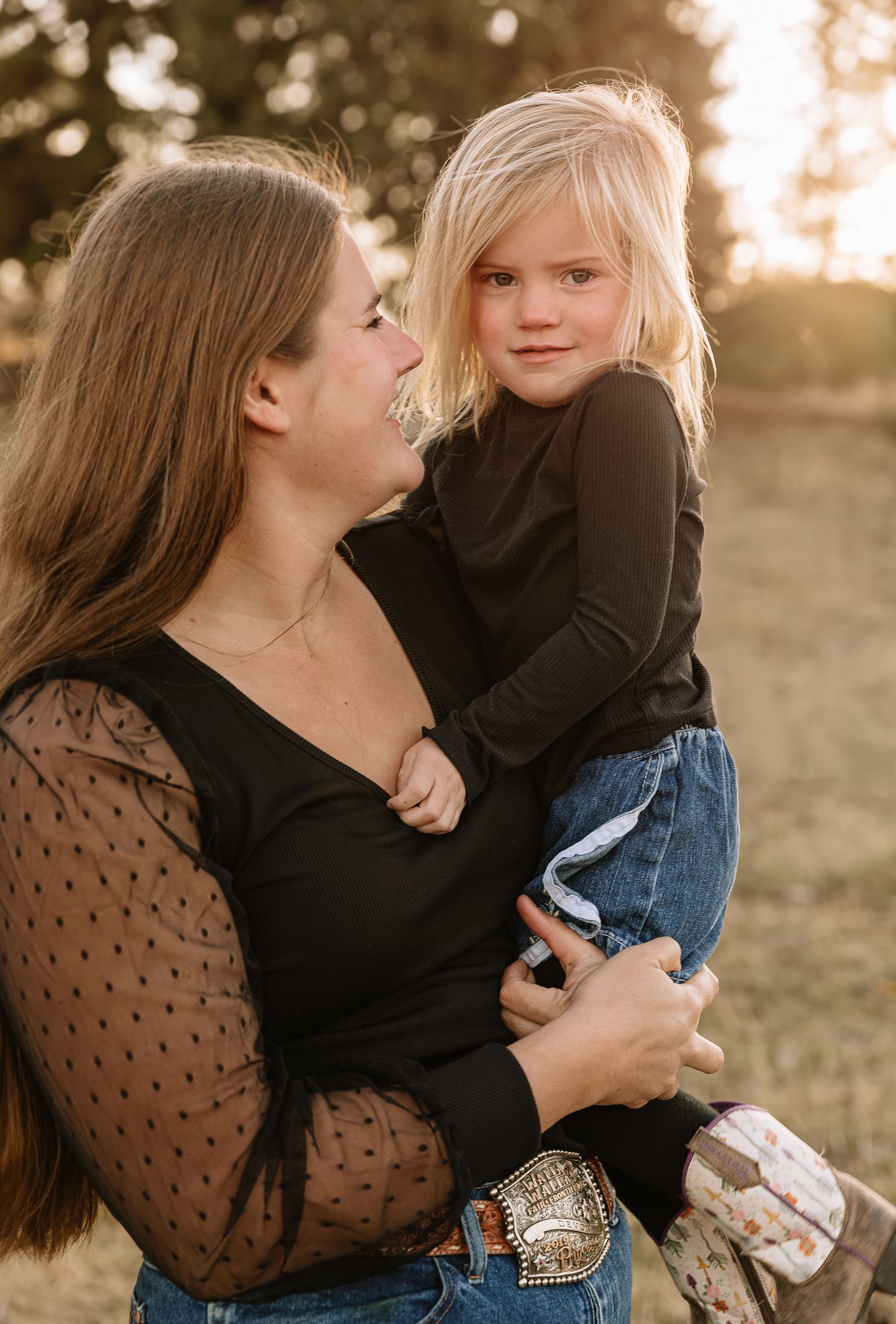 A tender moment captured at sunset showing a parent and child embracing in a field with golden light.