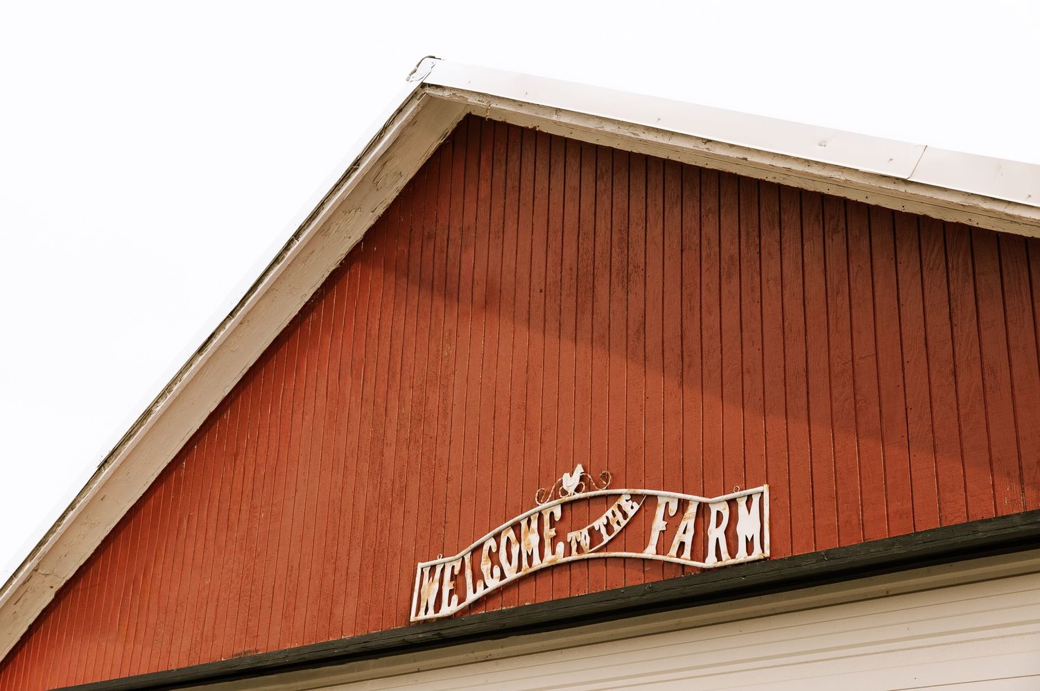 Red barn with white trim stands against a cloudy sky in a rustic farm setting.