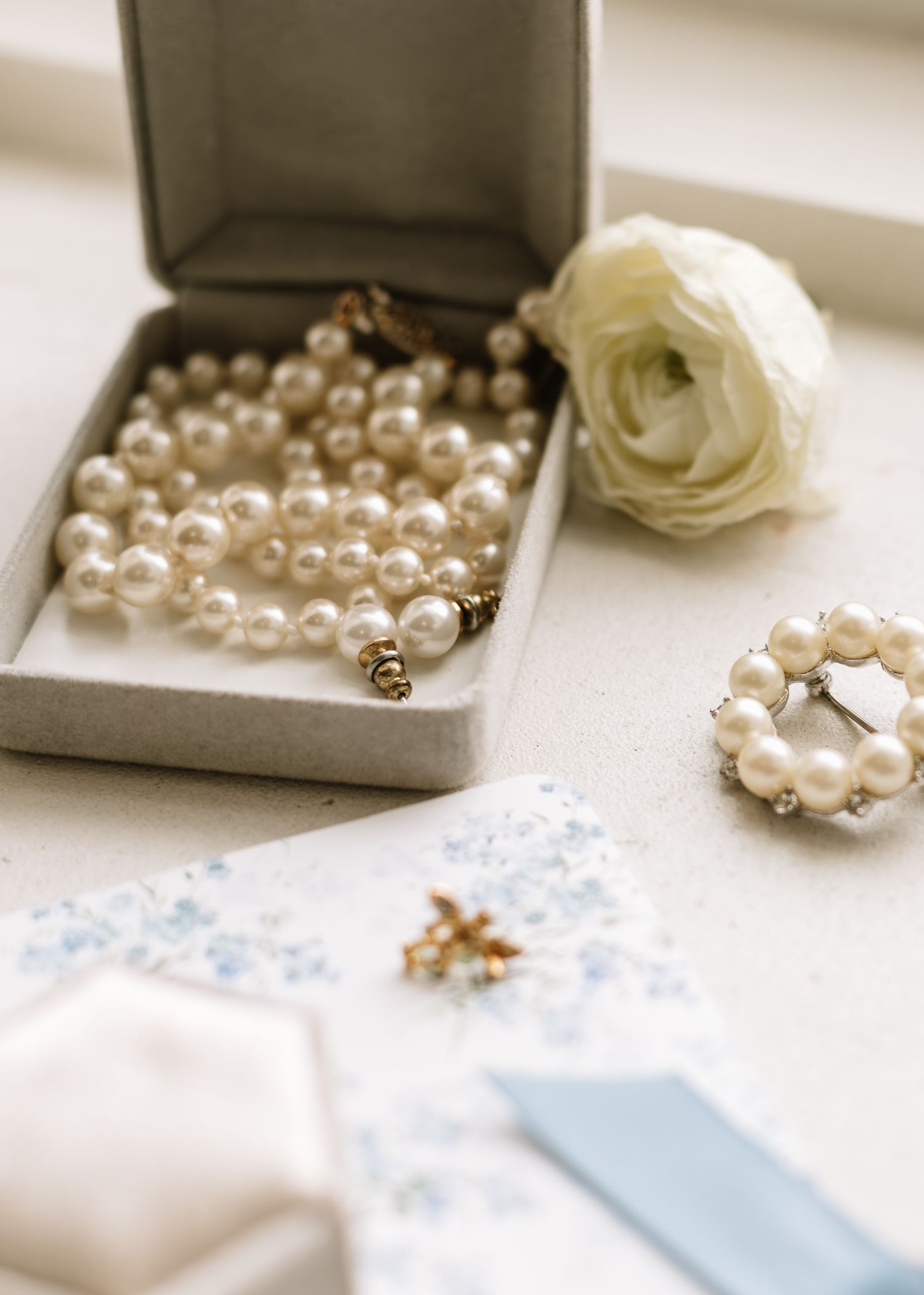 Pearl necklace and jewelry accessories arranged elegantly on a white surface with light blue accents.