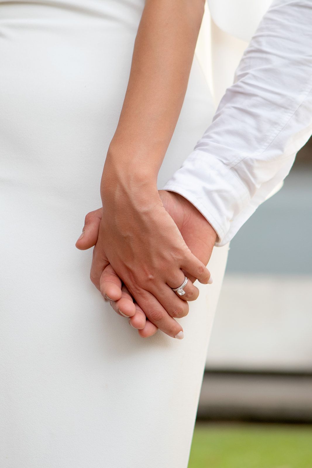 Close-up view of hands clasping together against a white background.