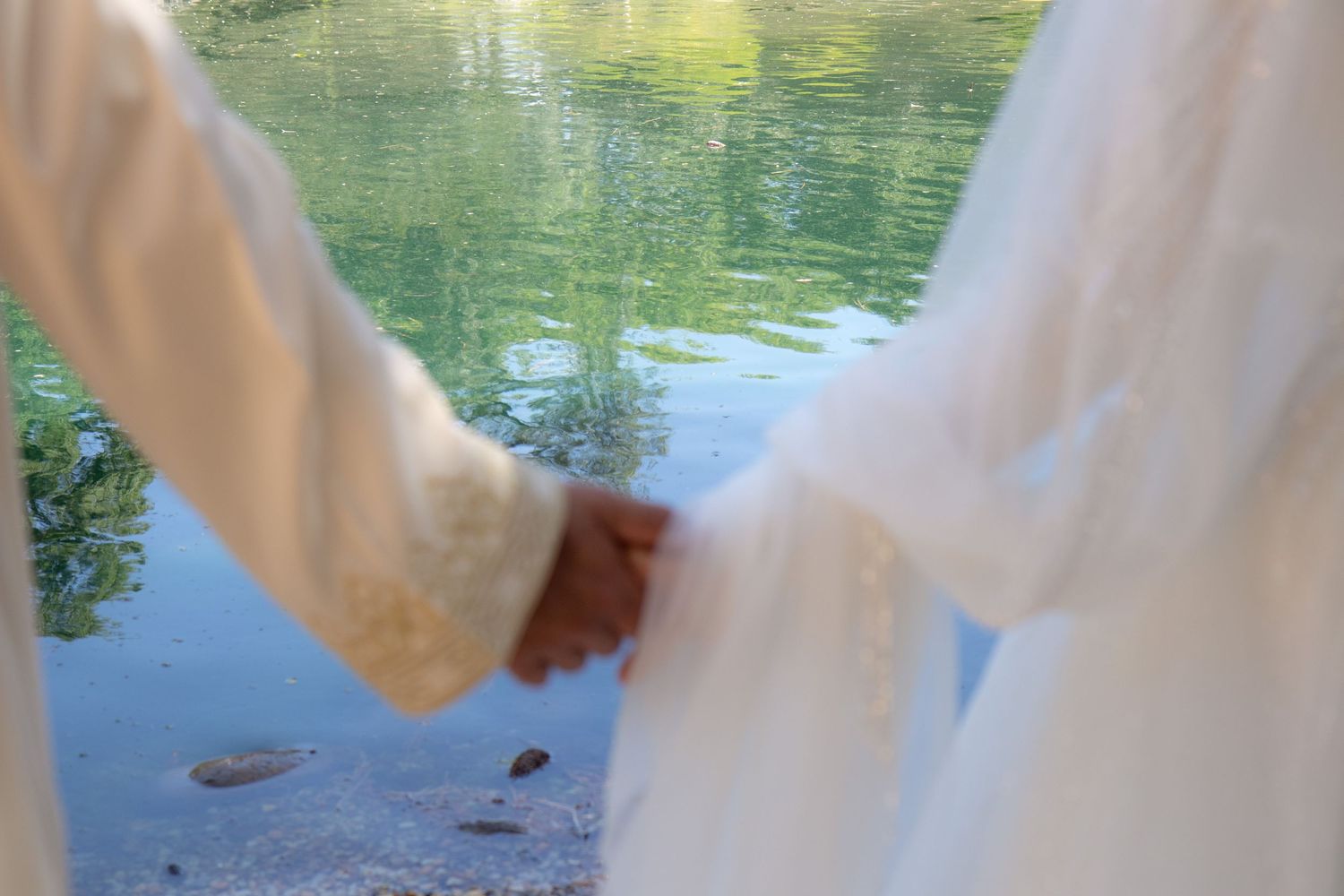 Reflections in tranquil green water with glimpses of white fabric at the edges.