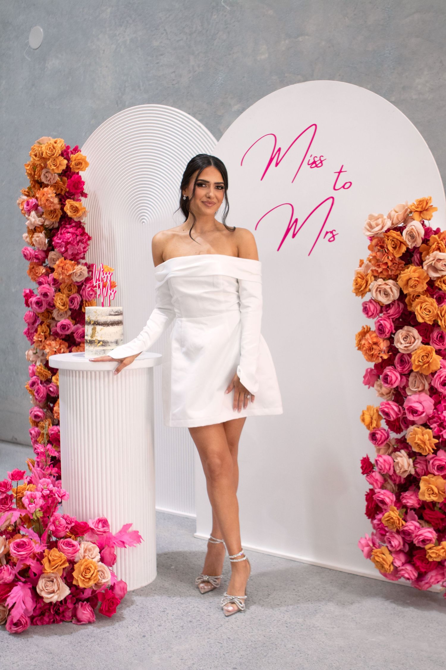Bridal photoshoot setup with pink and orange floral arrangements against a gray backdrop.