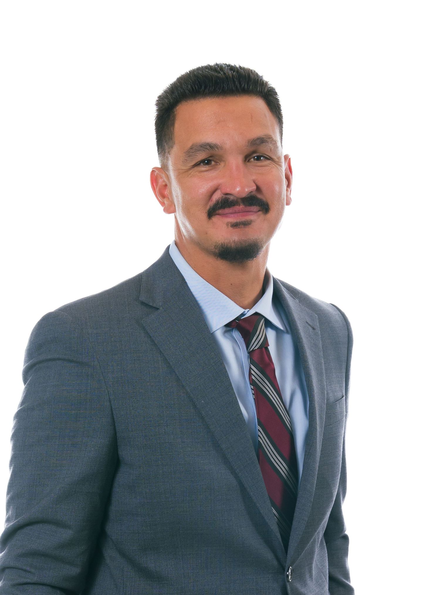Professional headshot portrait of person in grey suit and burgundy striped tie against light background.